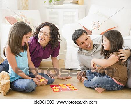 Stock Photo - Father and mother playing game in livingroom with children. Fotosearch