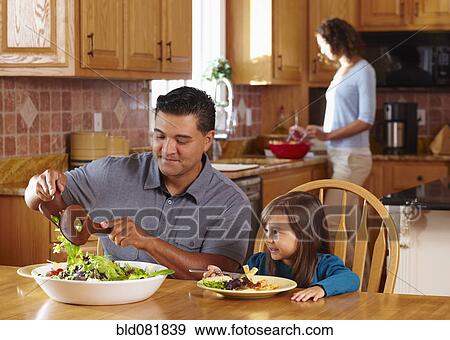 Stock Photo - Father serving daughter salad. Fotosearch