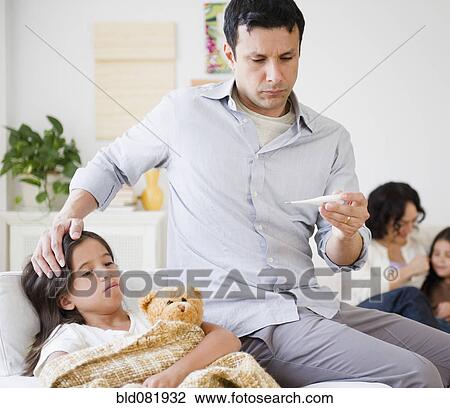 Stock Image - Father taking sick daughter's temperature with thermometer. Fotosearch