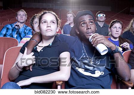 Stock Image - Friends watching movie in theater. Fotosearch