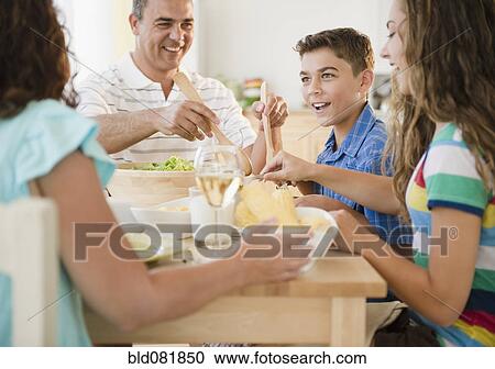 Stock Image - Happy family eating dinner together. Fotosearch