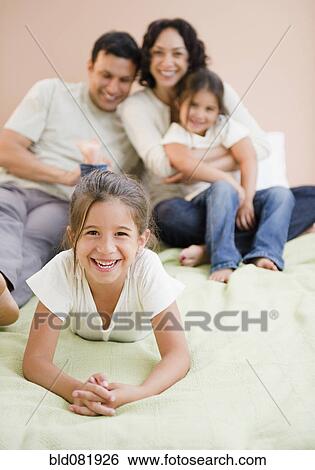 Stock Photograph - Happy family laying on bed together. Fotosearch
