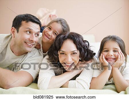 Stock Photography - Happy family laying on bed together. Fotosearch
