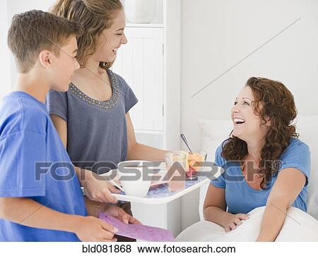 Stock Photo - Hispanic children bring mother breakfast in bed. Fotosearch