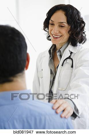 Stock Photo - Hispanic doctor talking to patient in doctor's office. Fotosearch