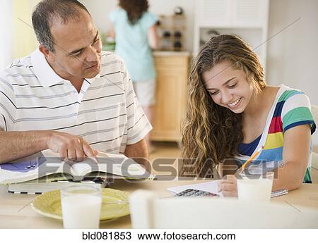 Stock Image - Hispanic father helping daughter with homework. Fotosearch
