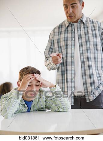 Stock Image - Hispanic father lecturing frustrated son. Fotosearch
