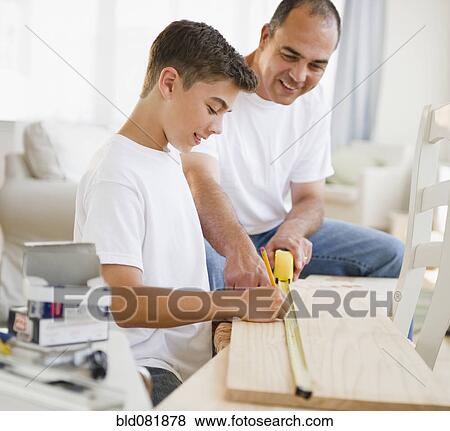 Stock Photo - Hispanic father teaching his son carpentry. Fotosearch