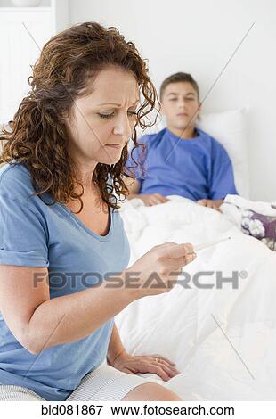 Stock Photo - Hispanic mother taking sick son's temperature. Fotosearch