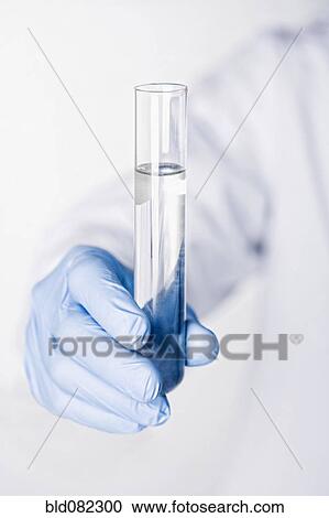 Stock Image - Hispanic scientist holding test tube full of water. Fotosearch