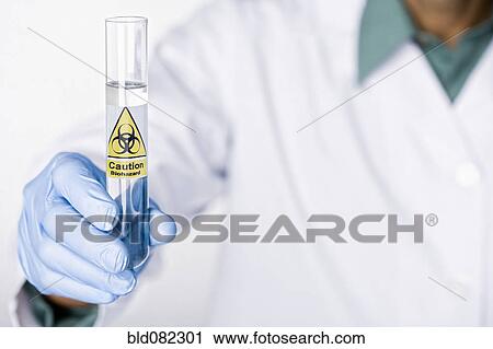 Stock Image - Hispanic scientist holding test tube with caution sticker full of water. Fotosearch