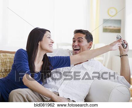 Laughing mixed race man keeping remote control away from wife View Large Photo Image Stock Image - Laughing mixed race man keeping remote control away from wife. Fotosearch