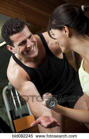 Stock Photography - Middle Eastern man helping woman lift weights. Fotosearch