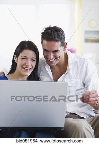 Picture - Mixed race couple shopping online with credit card. Fotosearch