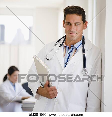 Stock Image - Mixed race doctor holding medical record in doctor's office. Fotosearch