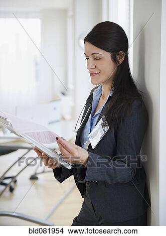 Picture - Mixed race doctor looking at medical record in hospital. Fotosearch
