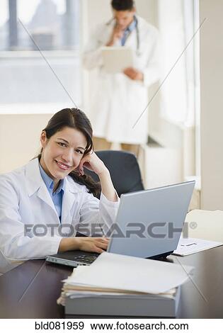 Stock Photo - Mixed race doctor working on laptop. Fotosearch