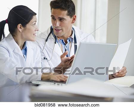 Stock Photo - Mixed race doctors working together on laptop. Fotosearch