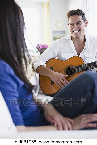 Stock Photography - Mixed race man playing guitar for wife. Fotosearch