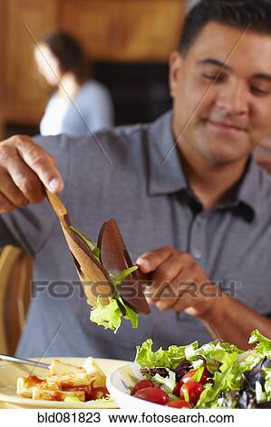 Mixed race man serving himself salad View Large Photo Image Stock Image - Mixed race man serving himself salad. Fotosearch
