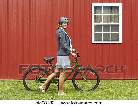 Stock Image - Mixed race woman in helmet standing with bicycle. Fotosearch