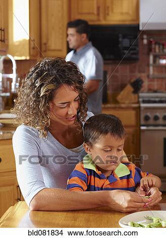 Mother and son shelling peas at dining table View Large Photo Image Picture - Mother and son shelling peas at dining table. Fotosearch