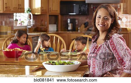 Stock Image - Mother serving salad to children. Fotosearch