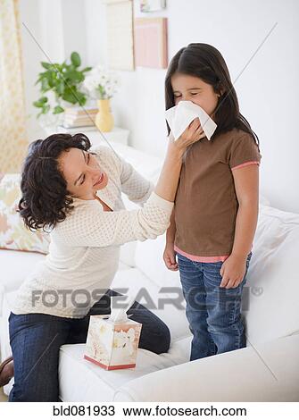 Stock Image - Mother wiping sick daughter's nose with tissue. Fotosearch
