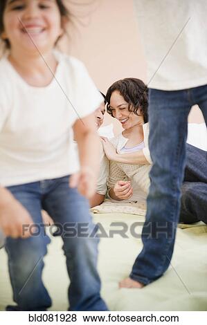Parents watching daughters jumping on bed View Large Photo Image Stock Photo - Parents watching daughters jumping on bed. Fotosearch