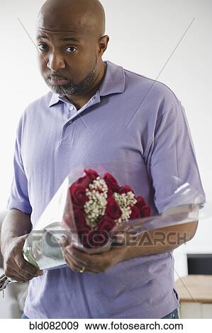 Stock Photo - Sad African American man holding bouquet of roses. Fotosearch