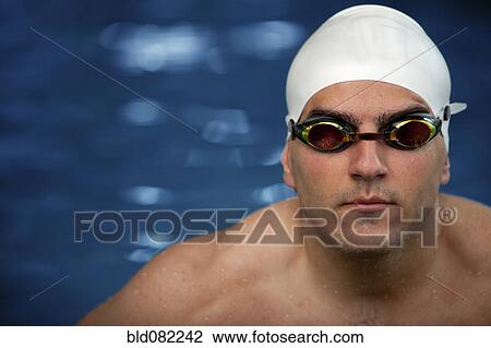 Stock Image - Serious Middle Eastern swimmer in swim cap and goggles. Fotosearch