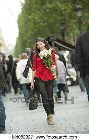 Stock Photo - Smiling Caucasian woman walking with bouquet. Fotosearch