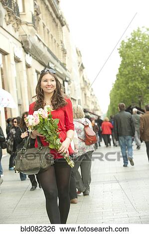 Stock Photograph - Smiling Caucasian woman walking with bouquet. Fotosearch