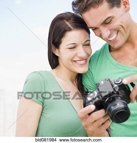Picture - Smiling couple looking at back of digital camera together. Fotosearch