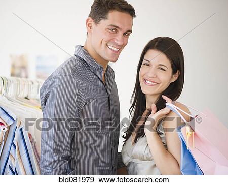 Stock Photo - Smiling couple shopping for clothing together. Fotosearch