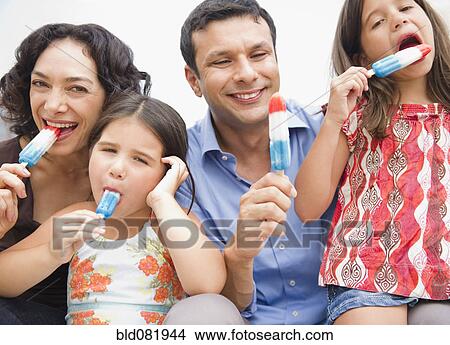 Smiling family eating popsicles together View Large Photo Image Picture - Smiling family eating popsicles together. Fotosearch