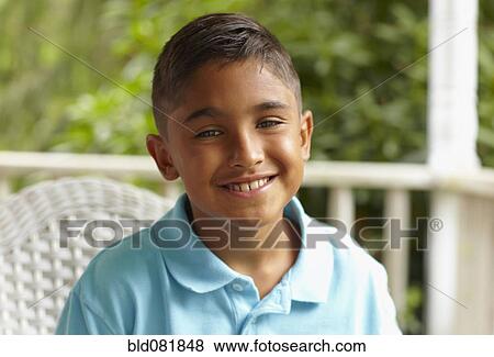 Stock Photo - Smiling Hispanic boy sitting on porch. Fotosearch