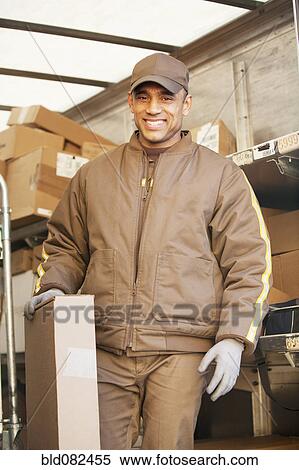 Smiling Hispanic delivery man holding cardboard box View Large Photo Image Stock Photography - Smiling Hispanic delivery man holding cardboard box. Fotosearch