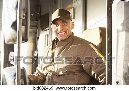 Stock Photo - Smiling Hispanic delivery man sitting in truck. Fotosearch