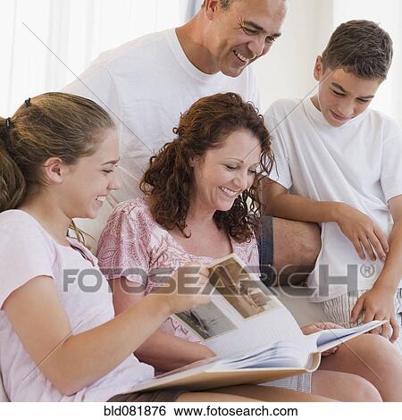Stock Photograph - Smiling Hispanic family looking at photo album together. Fotosearch