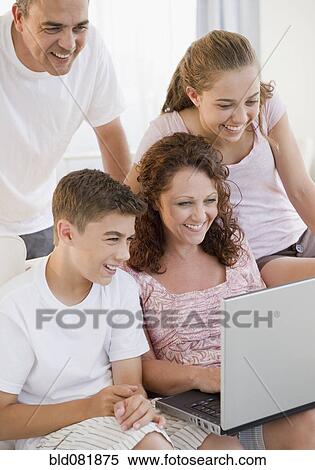 Stock Photography - Smiling Hispanic family using laptop together. Fotosearch