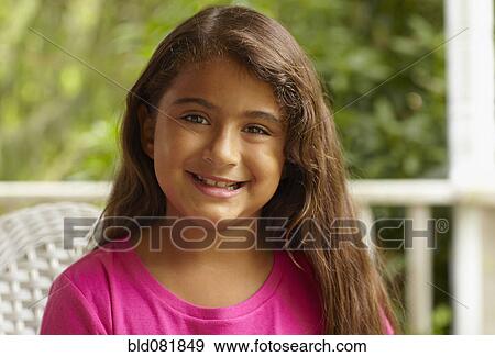 Stock Photo - Smiling Hispanic girl sitting in porch. Fotosearch
