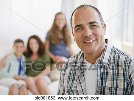 Stock Image - Smiling Hispanic man with family in background. Fotosearch