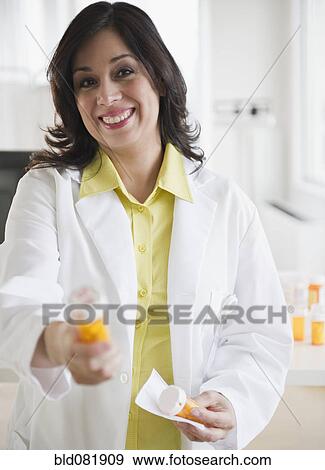 Smiling Hispanic pharmacist holding out prescription bottle View Large Photo Image Stock Photo - Smiling Hispanic pharmacist holding out prescription bottle. Fotosearch