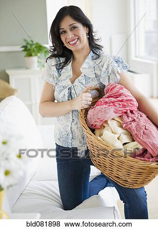 Stock Photo - Smiling Hispanic woman carrying basket of laundry. Fotosearch