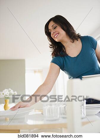 Smiling Hispanic woman setting dining table View Large Photo Image Picture - Smiling Hispanic woman setting dining table. Fotosearch