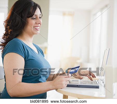 Smiling Hispanic woman shopping online with credit card View Large Photo Image Stock Photography - Smiling Hispanic woman shopping online with credit card. Fotosearch