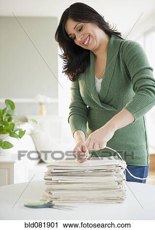 Smiling Hispanic woman trying newspapers in bundle View Large Photo Image Stock Image - Smiling Hispanic woman trying newspapers in bundle. Fotosearch
