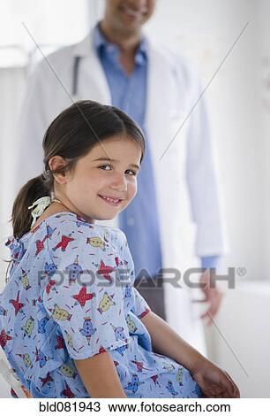 Smiling mixed race girl in examination room with doctor in background View Large Photo Image Stock Image - Smiling mixed race girl in examination room with doctor in background. Fotosearch