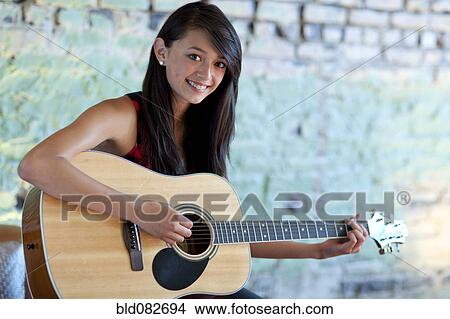Asian girl strumming guitar View Large Photo Image Picture - Asian girl strumming guitar. Fotosearch